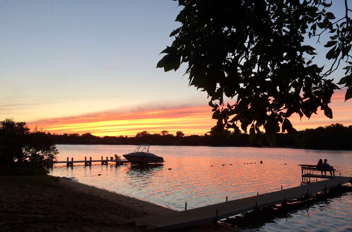 sunset view over a lake with a boat at the doc