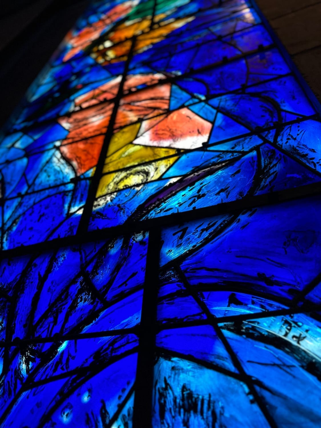 Blue stained glass window with red and gold Chagall design