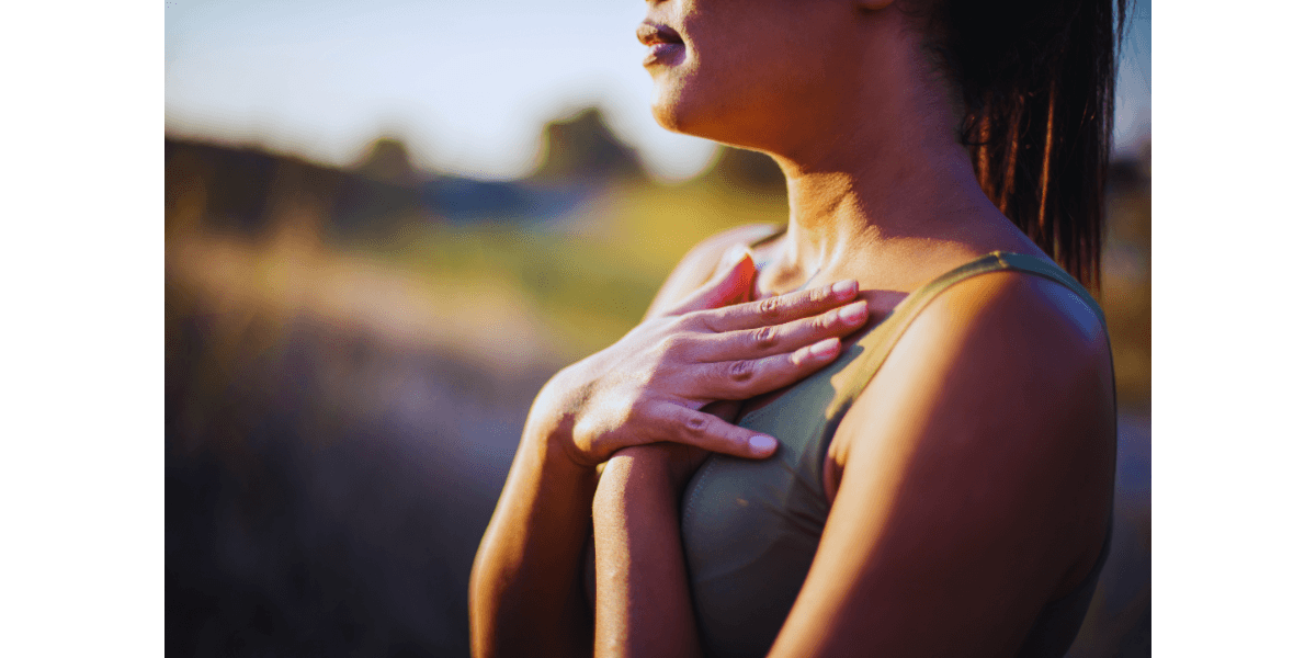 woman in a yoga top with arms crossed over chest grounding herself