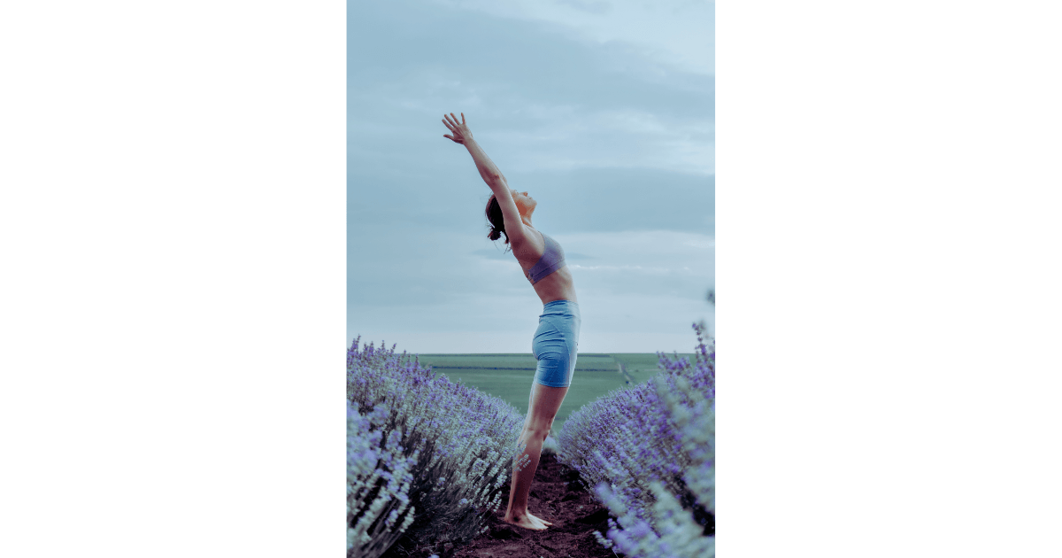 caucasian woman with outstretched arms in yoga pose in lavender field