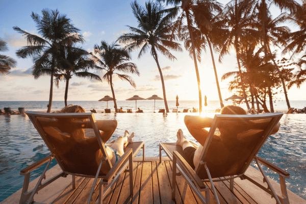 Why Boundaries Are Your Superpower in Recovering from Narcissistic Abuse - image of 2 people sitting around an infinity pool, having established boundaries and surrounded by palm trees