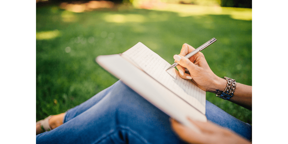 hands of woman with a journal propped on her bluejeans-clad knees