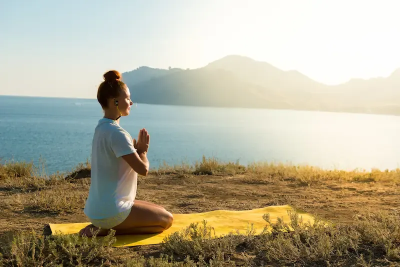 Indian woman in yogi pose, seated with arms outstretched