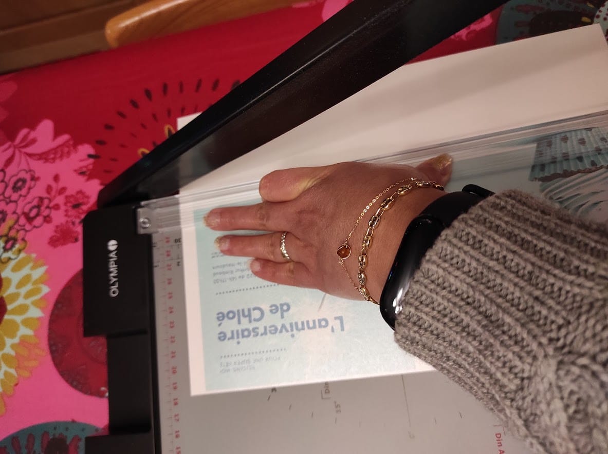 Photo avant : une main découpant une invitation imprimée au massicot