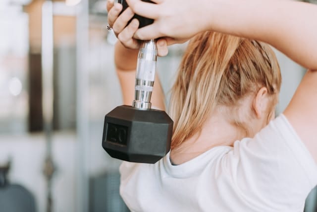 Woman in white tee shirt lifting weights