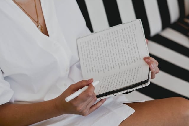 woman in white seated and journaling