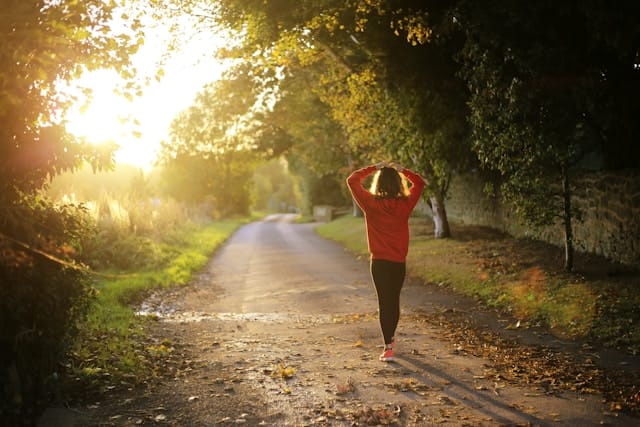 Woman in red tennis shoes and shirt walking on dirt road