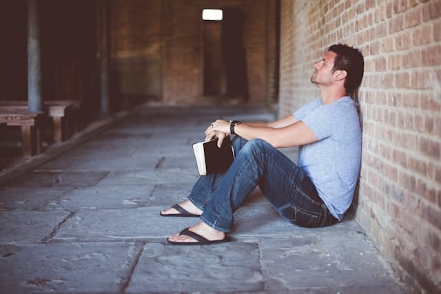 Man reading personal growth book sits reflecting after