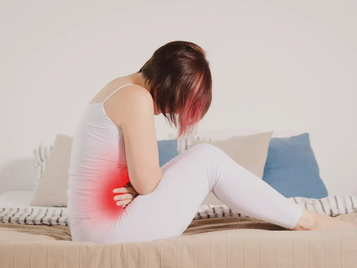 Woman holding her stomach in pain from IBS symptoms like bloating, diarrhea, or constipation