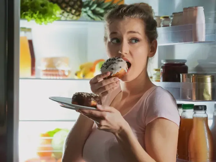 Woman craving sugar at night, with gut bacteria concept overlay to represent how microbiota influence food choices.