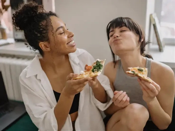 Two women enjoying pizza and relaxed eating without strict dieting