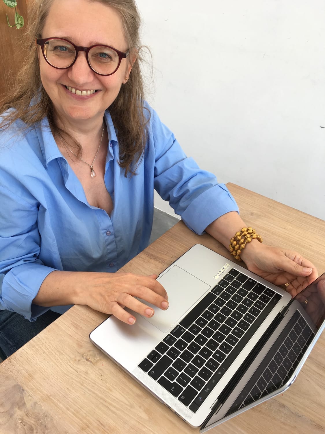 woman smiling sitting at a table with laptop computer open