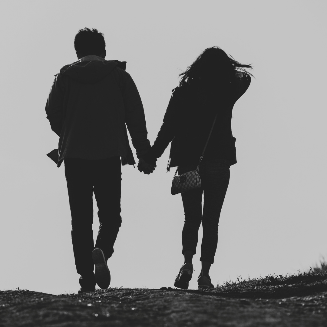 un couple marchant côte à côte sur un chemin de montagne, dans une lumière douce et dorée, symbolisant l'élévation, la bonne entente, une communication efficace, sereine, équilibrée et durable