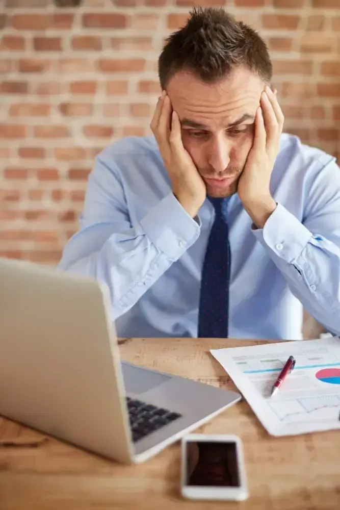 Entrepreneur stressé devant son ordinateur à cause d’une erreur comptable ou d’un dossier fiscal mal géré.