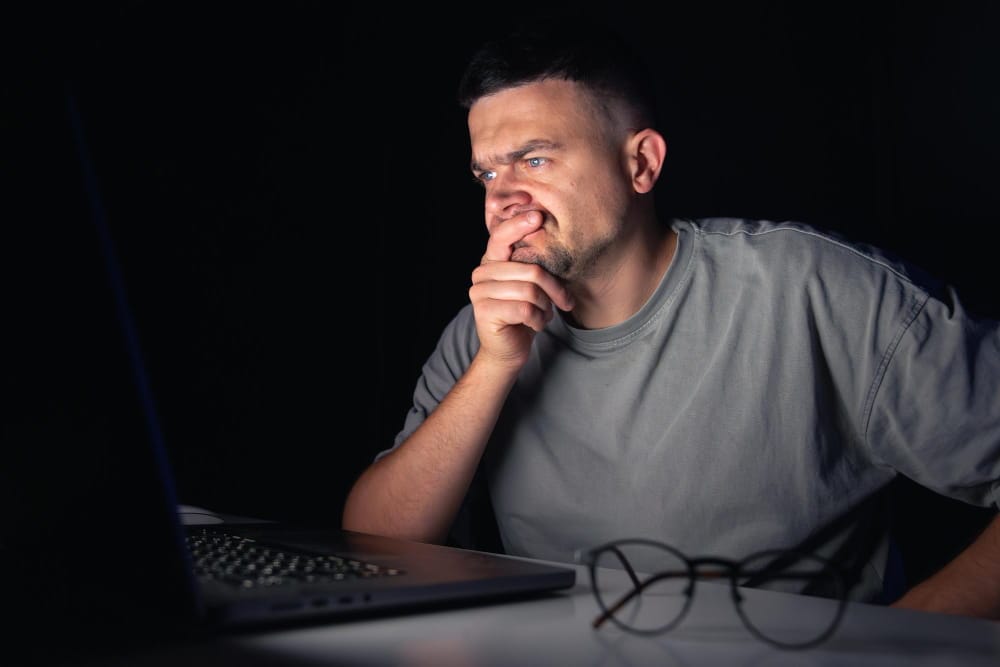Developer working late at night looking worried at a laptop, illustrating the stress of unreliable Python web hosting