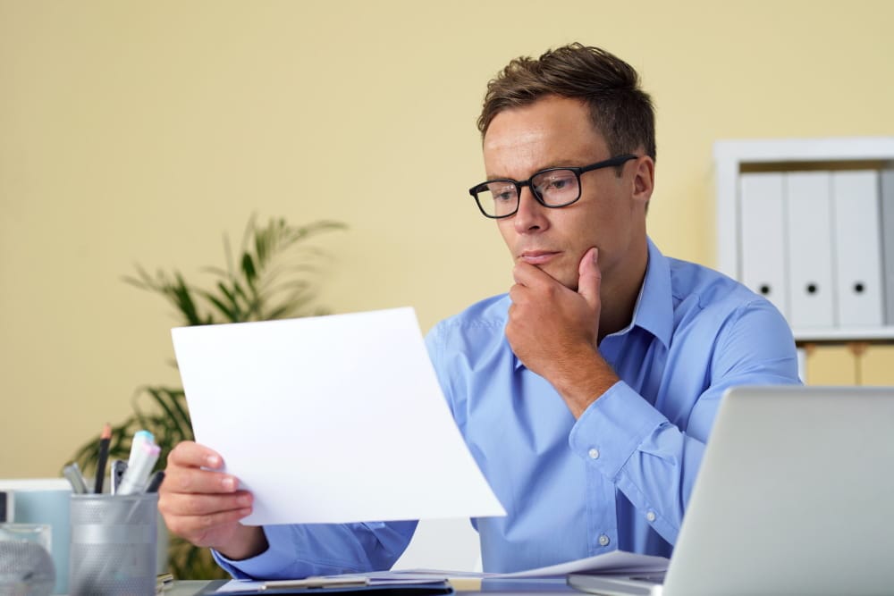 Dirigeant d'entreprise lisant un courrier d'un air préoccupé à son bureau