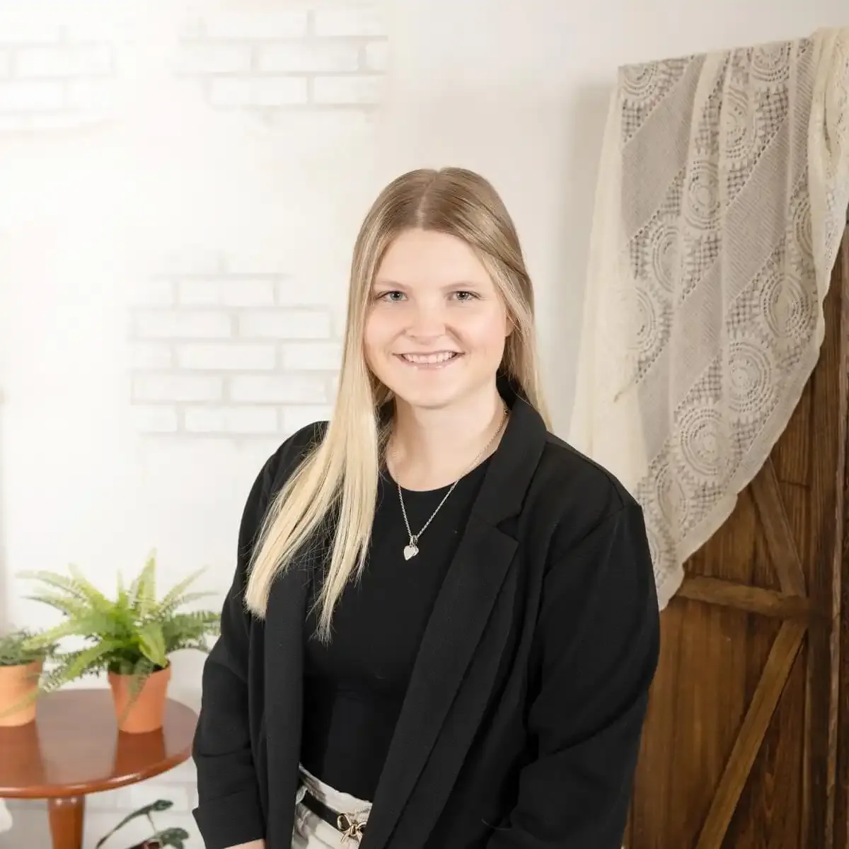 A smiling professional woman, Courtney, in a blazer, representing the dedicated team delivering high-level business growth strategies.