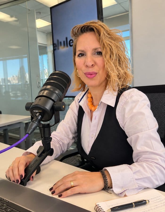 Ani Olivera en un estudio de podcast, sonriendo frente al micrófono