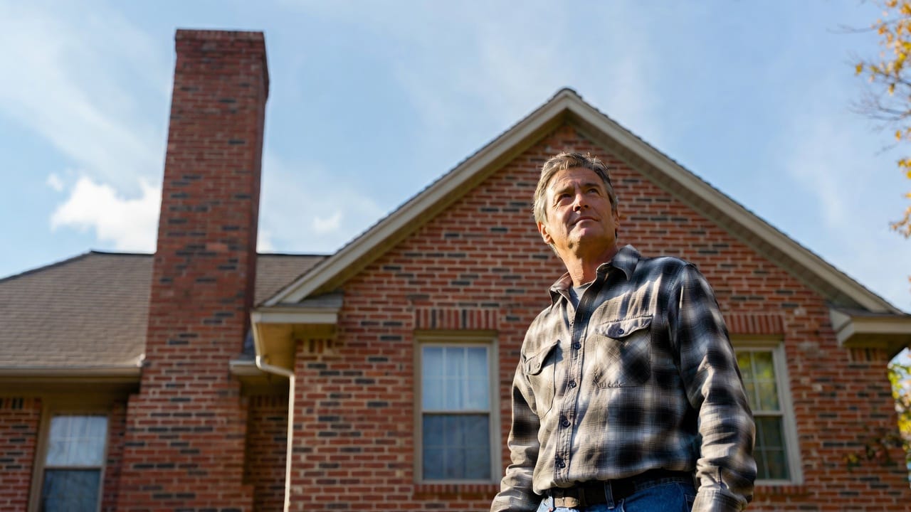 Confident homeowner standing in front of well-maintained brick home with chimney