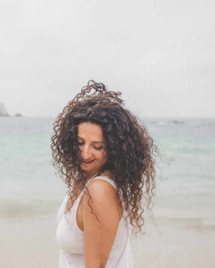 Marianella Ruiz en la playa, sonriendo con el pelo al viento