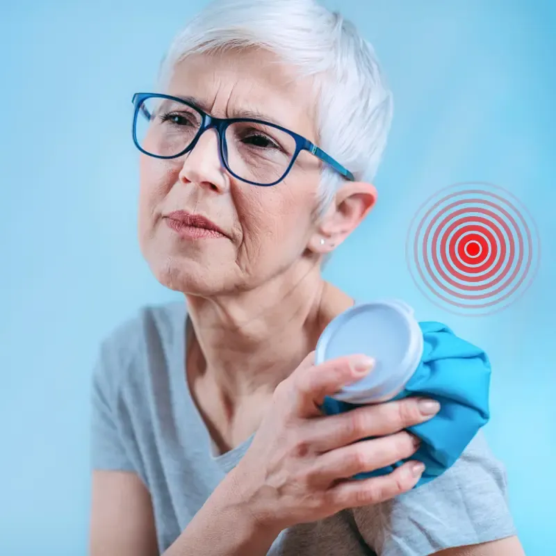 Woman over 50 holding painful shoulder, illustrating the cycle of neuroplastic pain.