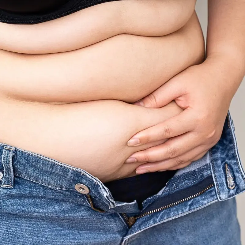 A woman over 50 pinching abdominal fat, highlighting how Vagus nerve dysfunction can affect fat storage in the midsection.