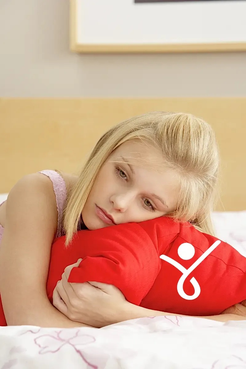 A young girl hugging a pillow, representing childhood issues can affect present behaviour
