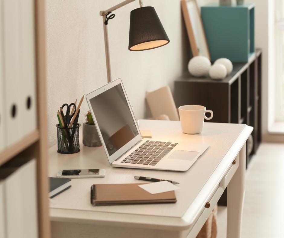 Woman working from home sitting on her couch using her laptop to work relaxing infront of a nice outside view