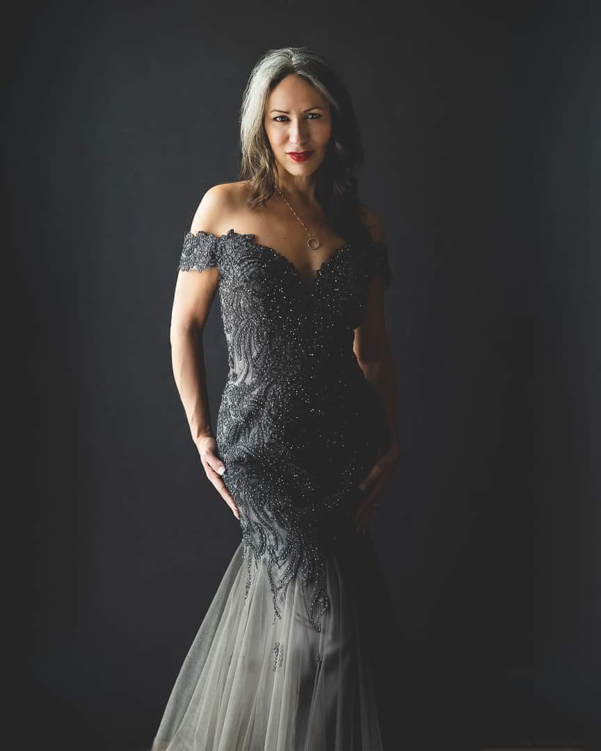 Elegant woman wrapped in burgundy tulle, surrounded by flowers during a luxury boudoir photoshoot in MIami, capturing beauty and sensuality in a studio setting in Miami.