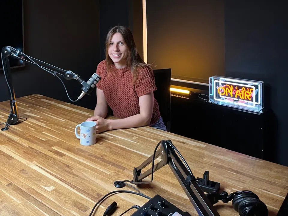 Julia Glazewska in a podcast studio, smiling at the microphone