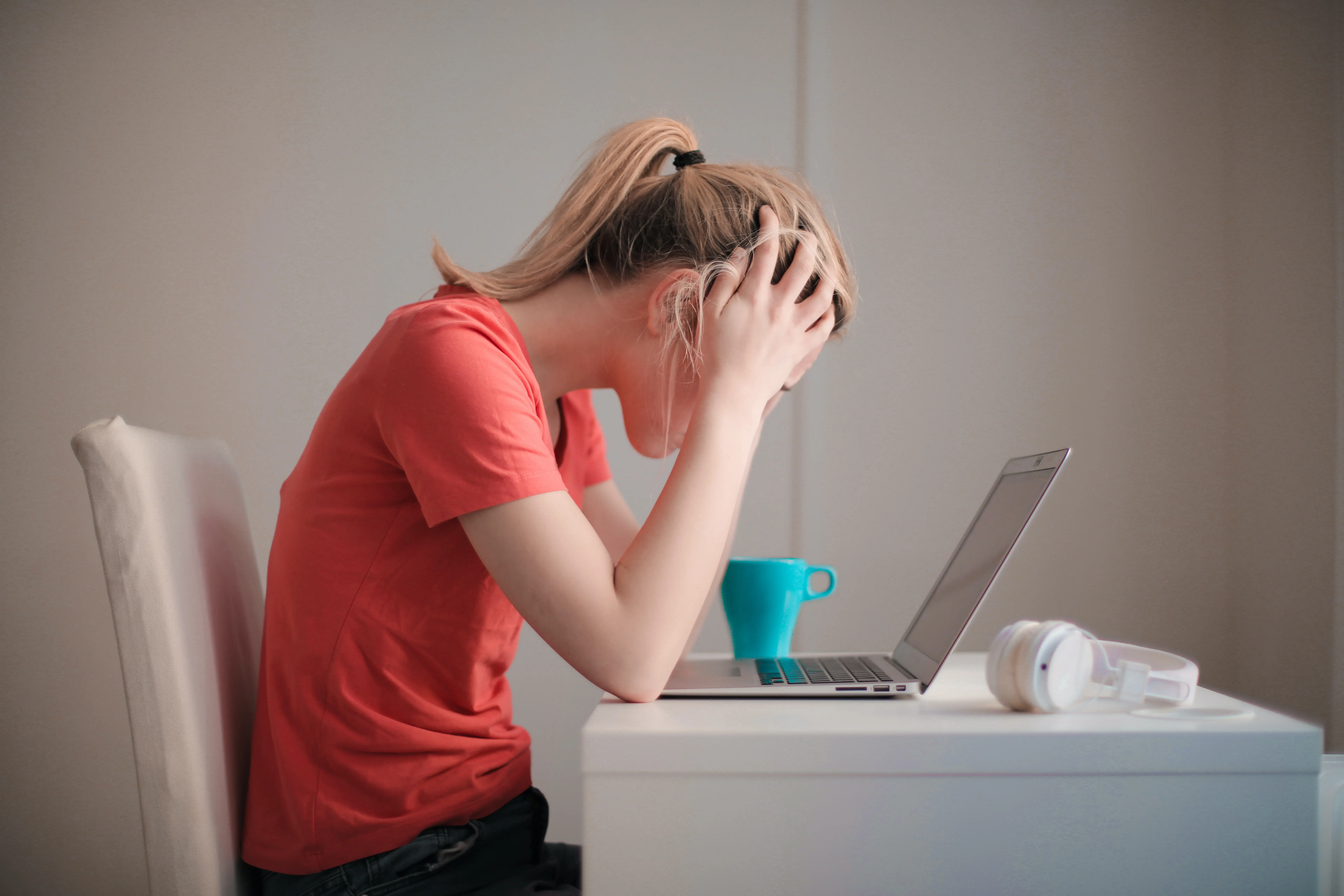 Femme désespérée devant son ordinateur, symbolisant les blocages des écrivains comme le syndrome de l'imposteur, la page blanche et la peur de l'échec