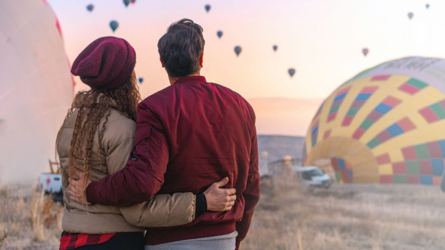Couple embracing and looking at hot air balloons