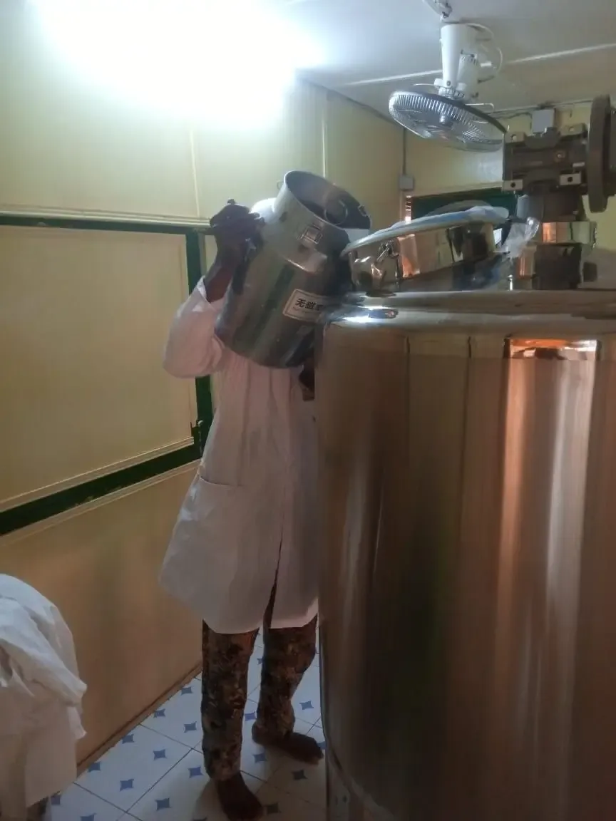 L’image montre un technicien en train d’introduire du lait dans une machine. Il s’agit d’une cuve industrielle en acier inoxydable, principalement utilisée dans l’industrie agroalimentaire, notamment pour la transformation des produits laitiers.