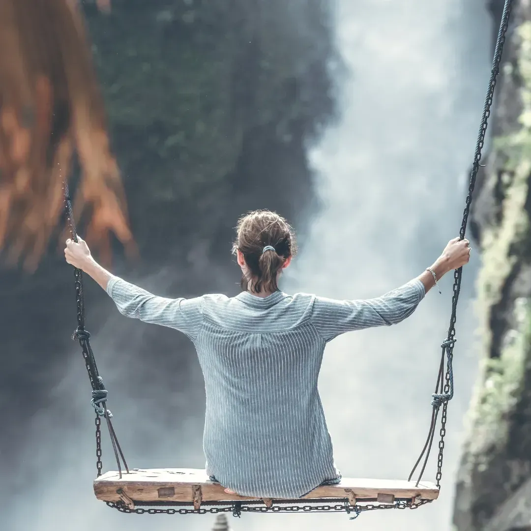 Frau auf einer Schaukel vor einem Wasserfall. Ein Blick auf den Wasserfall. Freiheit leben