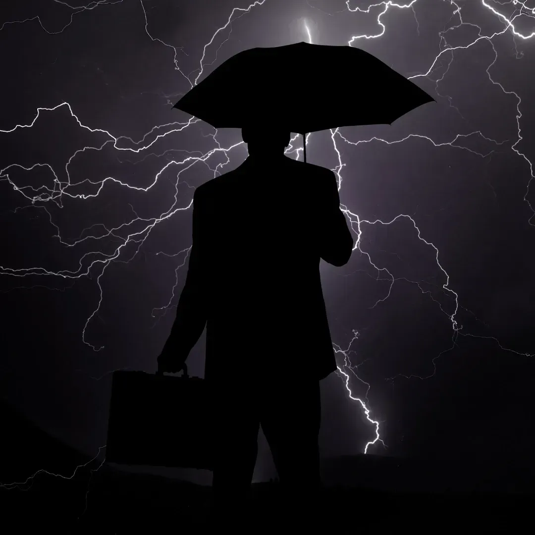 Person mit Regenschirm um ihn herum viele Blitze, dieses Bild steht symbolisch für eine Krise 