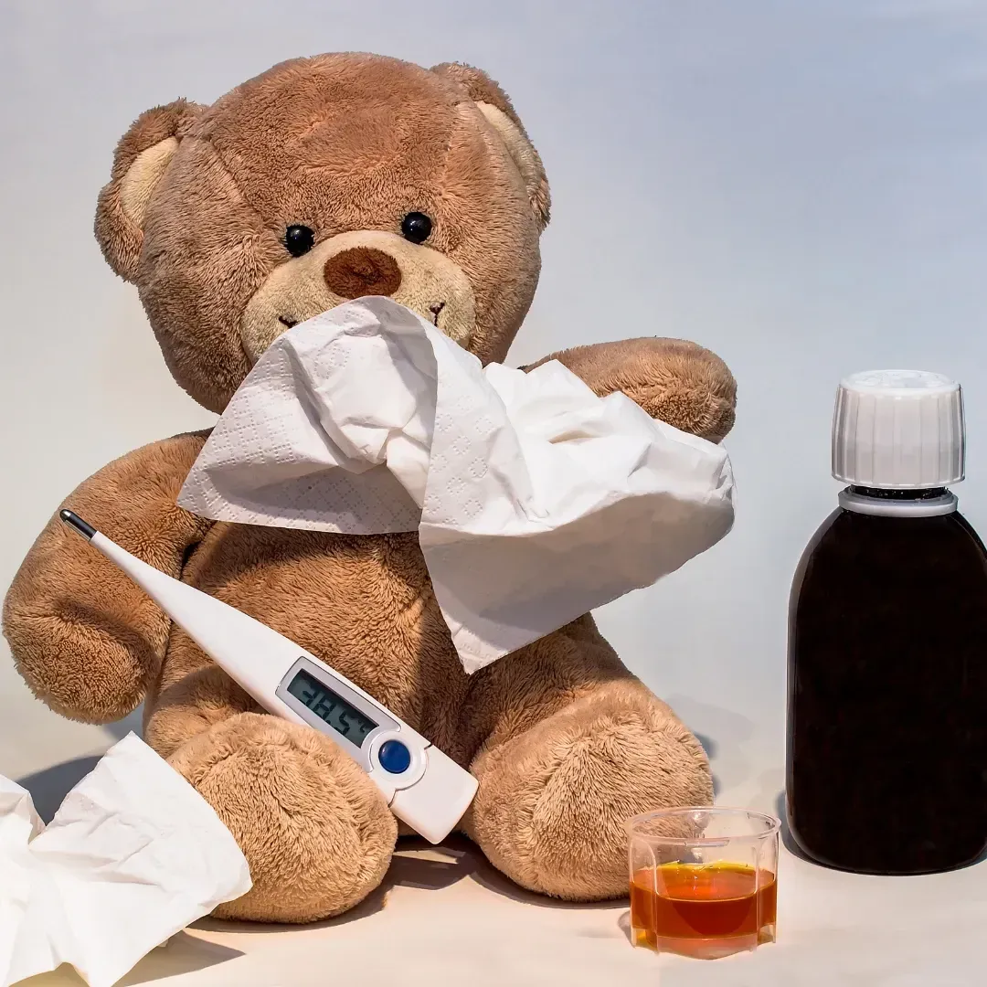 Teddybär mit Taschentuch und Fieberthermoether daneben eine Flasche mit Flüssigkeit, symbolisch steht das in meinem Beitrag für Kinderkrankheiten
