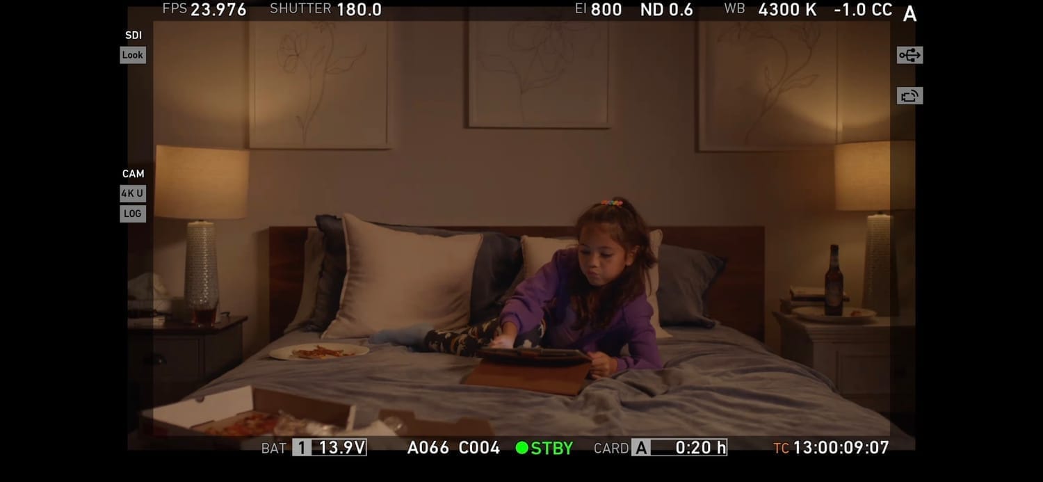 Vanessa Fox filming a bedroom scene in Pillow Talk, lying on the bed with a tablet.