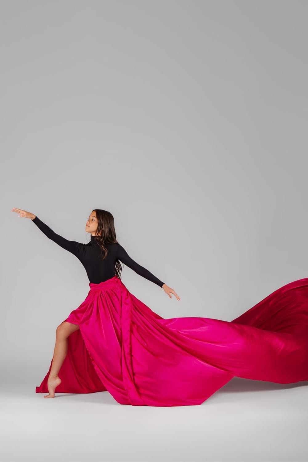 Vanessa Fox performing an expressive contemporary dance pose  in a flowing red fuschia during an editorial studio photoshoot.
