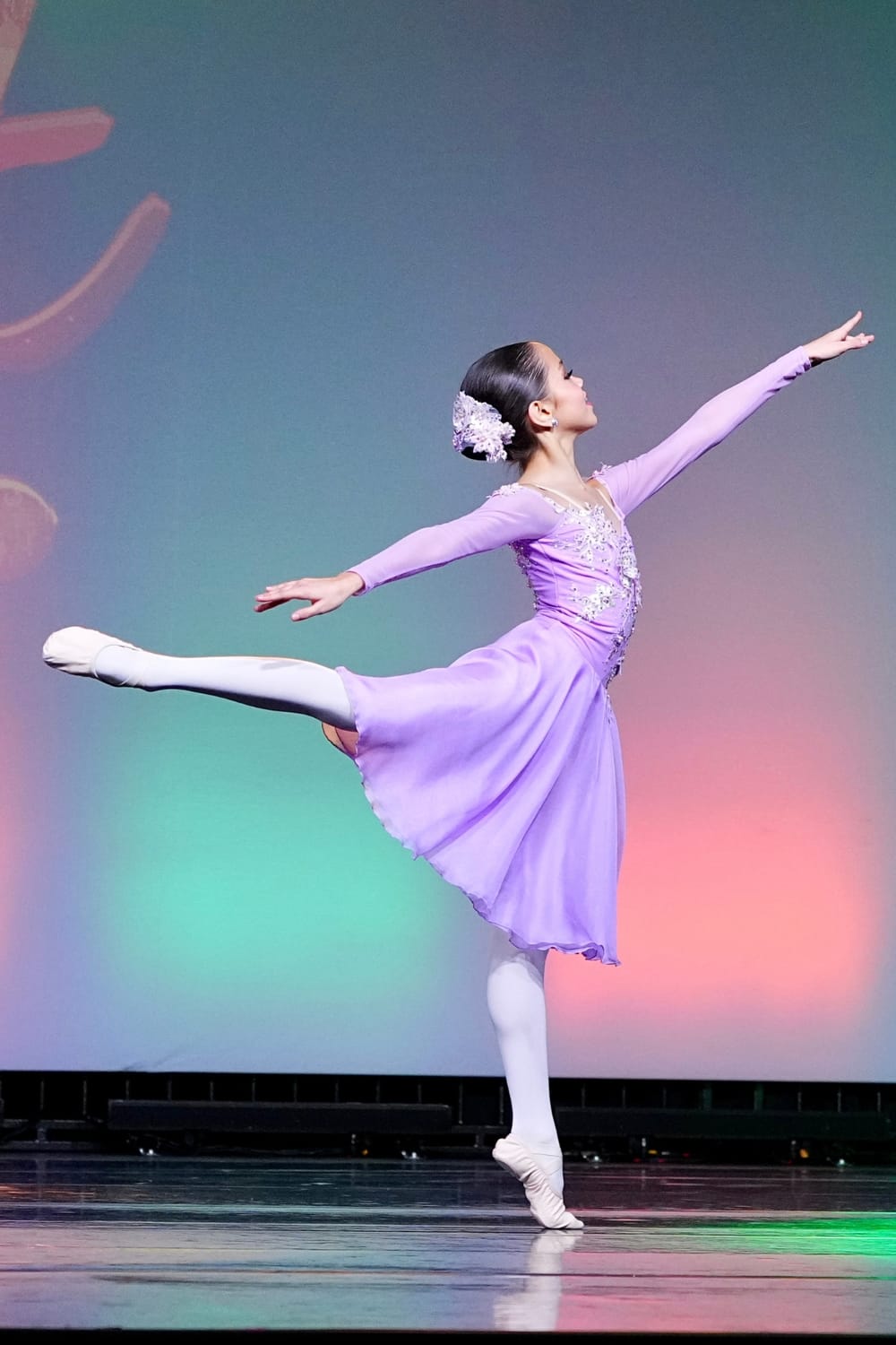 Vanessa Fox performing a ballet arabesque on stage during a dance competition.