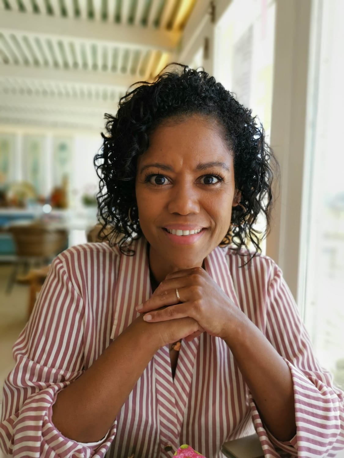 Smiling woman with black hair wearing a mint green blouse and black pants