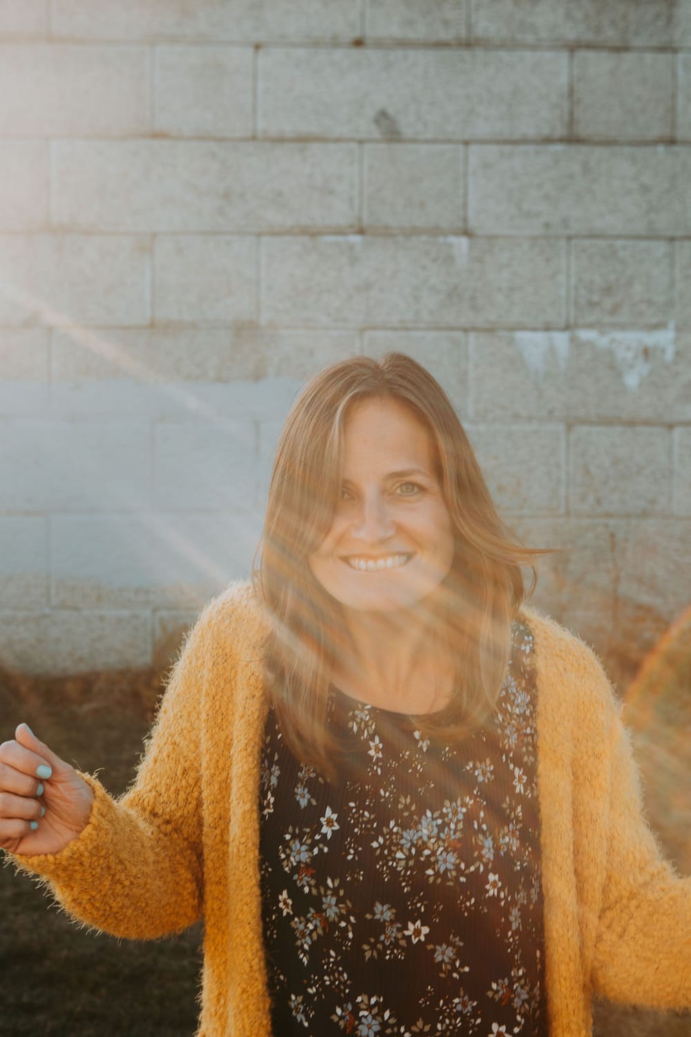 Kelly Taxter sitting on a wooden balance beam, in the woods, smiling