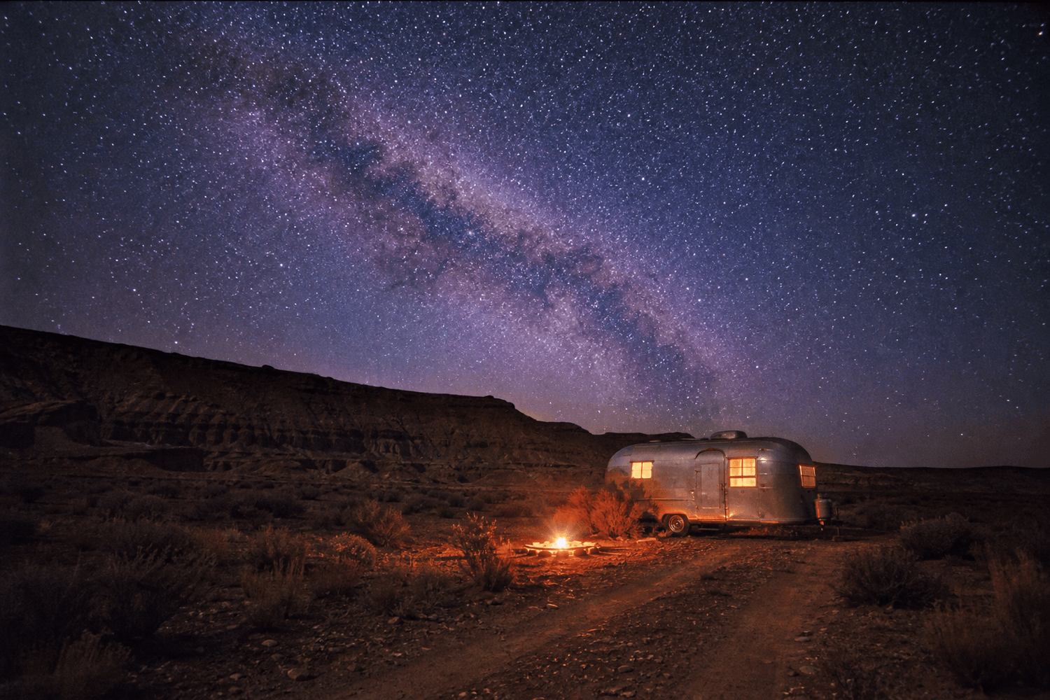 A vintage trailer and campfire under the Milky Way
