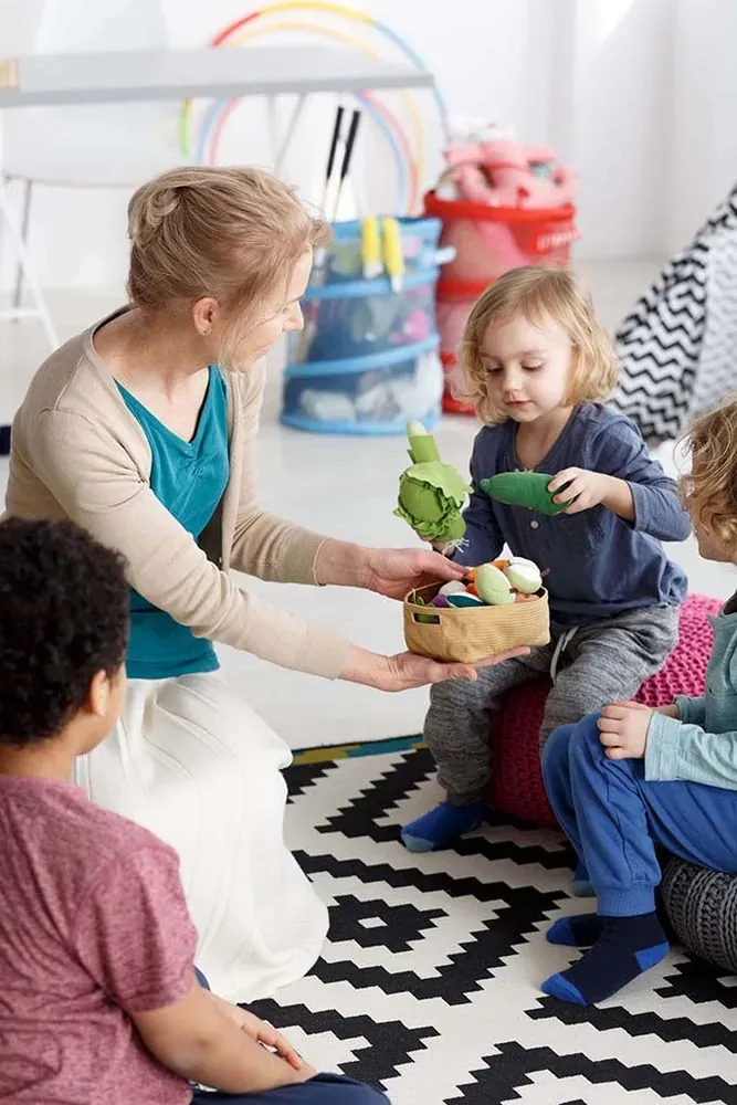 Une adulte et des enfants jouent avec des peluches