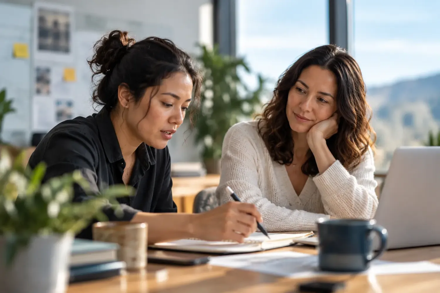 A leader working closely with a colleague at a desk, guiding rather than doing the work for them