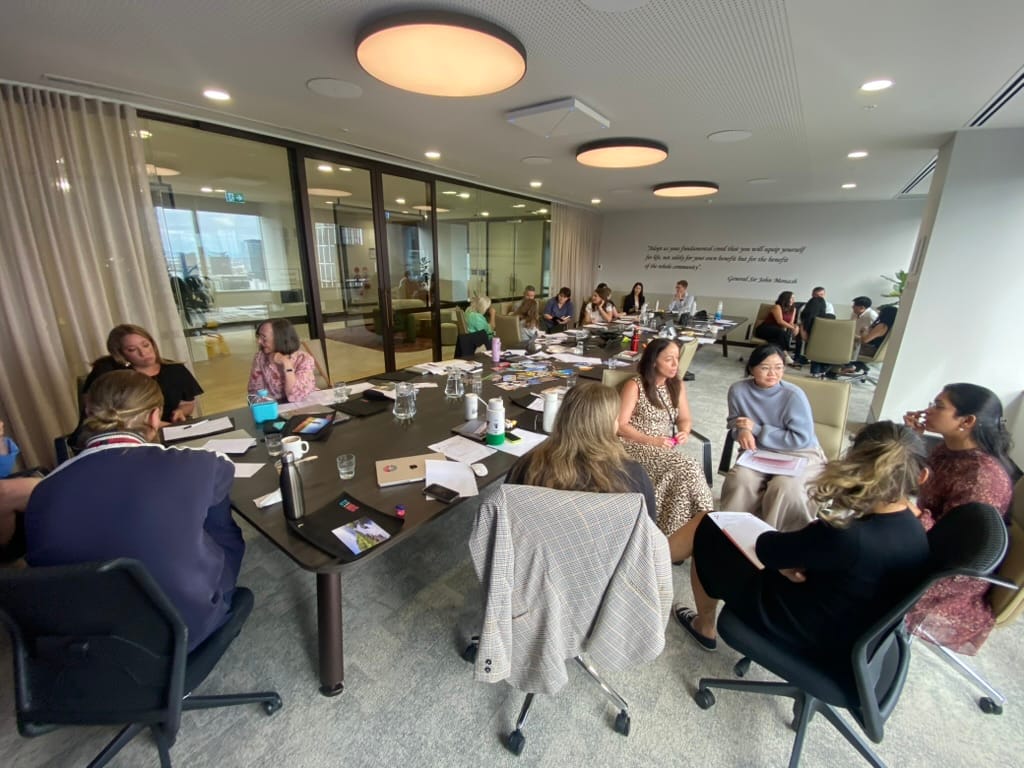 A group of workshop participants around a table during a CliftonStrengths session
