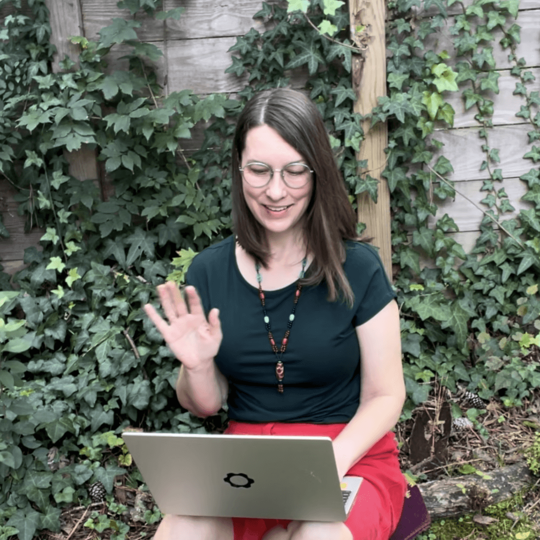 Image of Sarah Cooke waving to Zoom participants on laptop