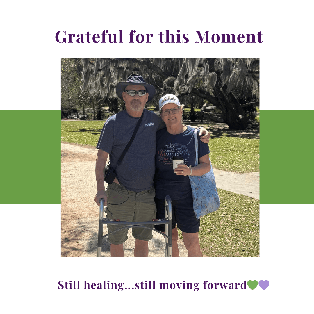 A couple standing together outdoors, smiling and embracing during recovery after a serious health event