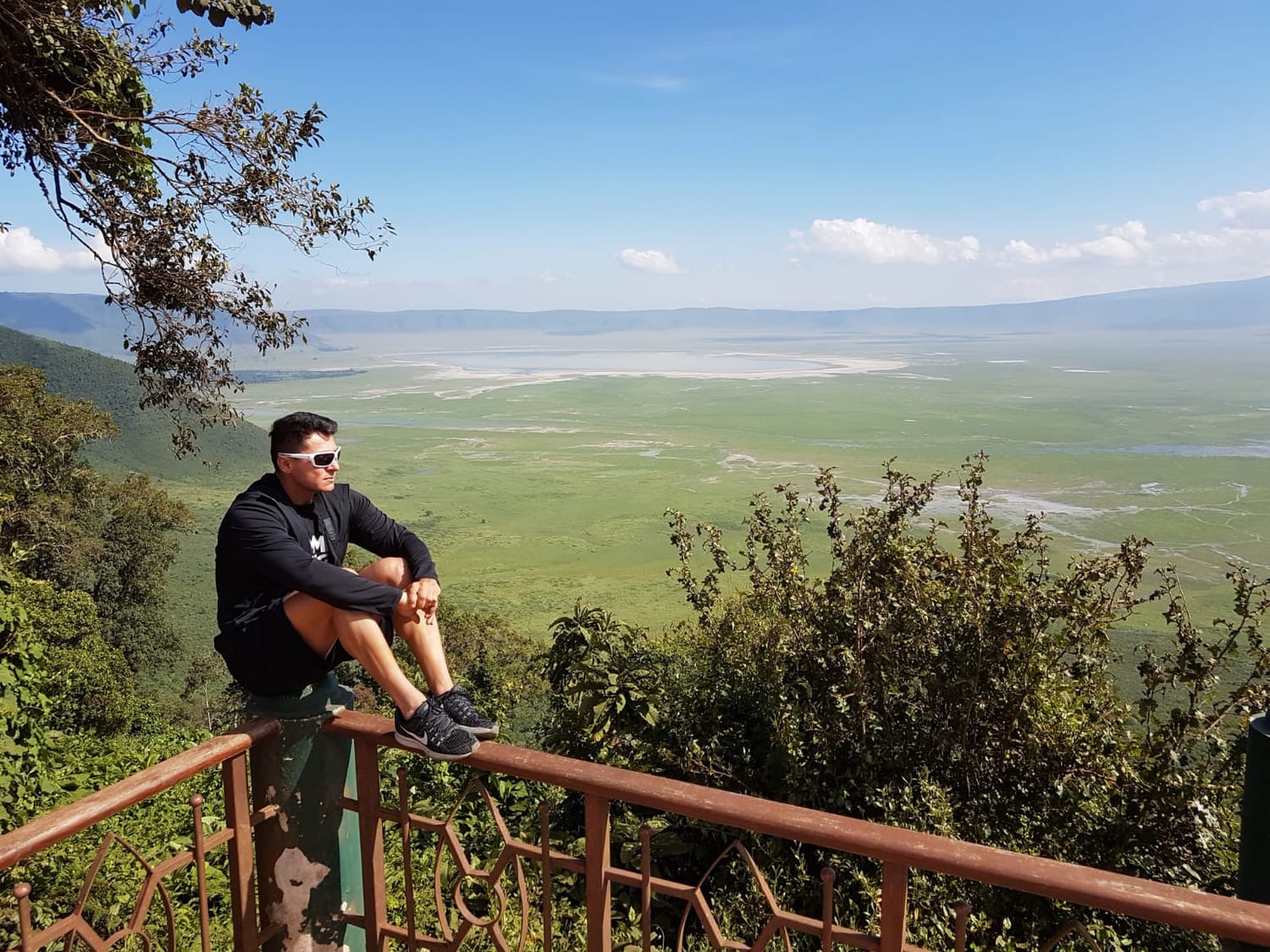 "Author contemplating a beautiful and serene natural landscape, surrounded by trees and mountains, with a reflective expression that suggests hope and anticipation for a bright future."