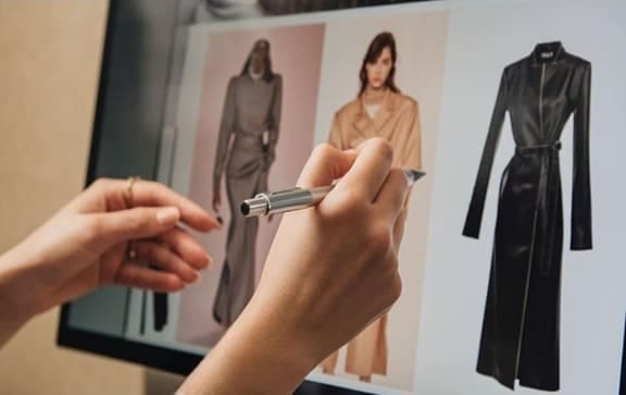 Manos señalando imágenes de estilismo en una pantalla digital, representando la asesoría de imagen personal.