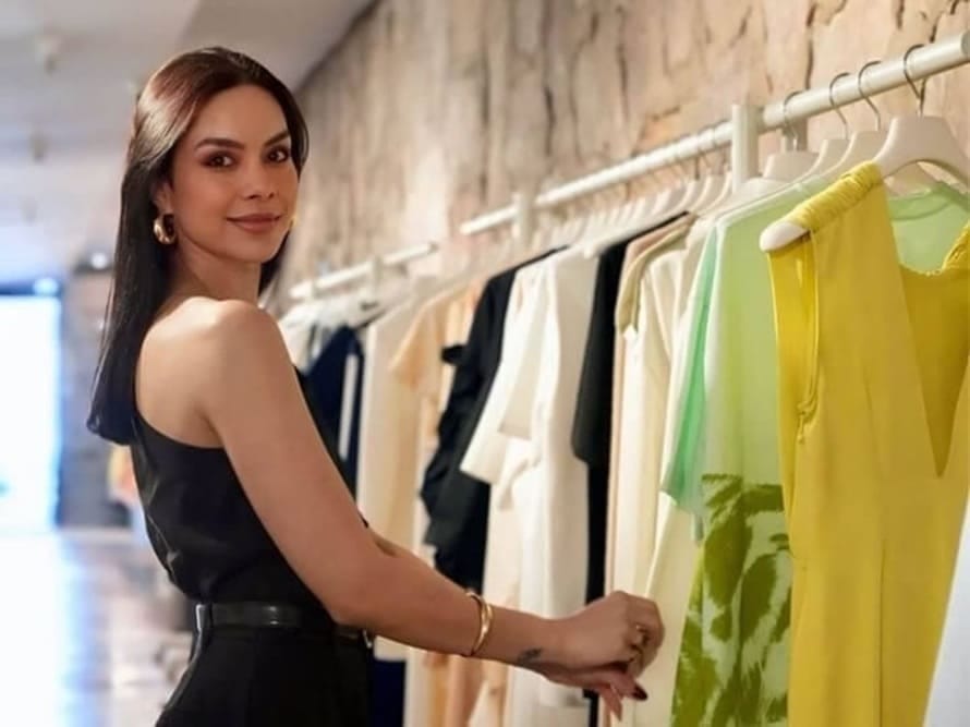 Mujer revisando prendas en un perchero dentro de una tienda de moda, representando la asesoría de imagen personal